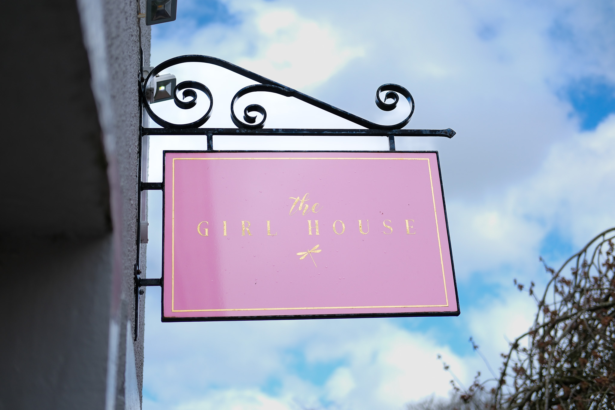The Girl House hanging sign in pink and gold